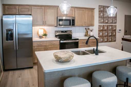 A kitchen with a refrigerator, microwave, oven, sink, and bar stools. at Grays Creek Apartments, Tennessee, 38018