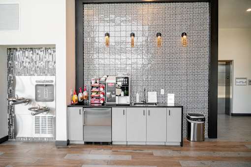 A modern kitchen area with a sink, refrigerator, and a wall of tiles at Harbor Side at Conwood Flats Apartments in Uptown Memphis, TN
