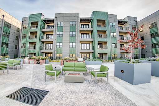 A courtyard with a bench and a tree in front of apartment buildings at Harbor Side at Conwood Flats Apartments, Memphis, TN, 38107