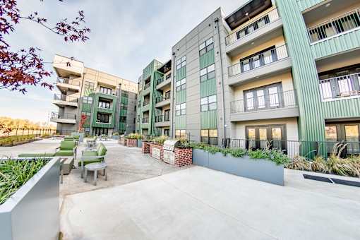 A modern apartment complex with a courtyard and greenery at Harbor Side at Conwood Flats Apartments, Memphis, TN, 38107