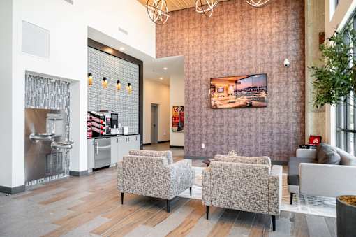 A modern living room with a grey sofa and a television on the wall at Harbor Side at Conwood Flats Apartments in Uptown Memphis, TN
