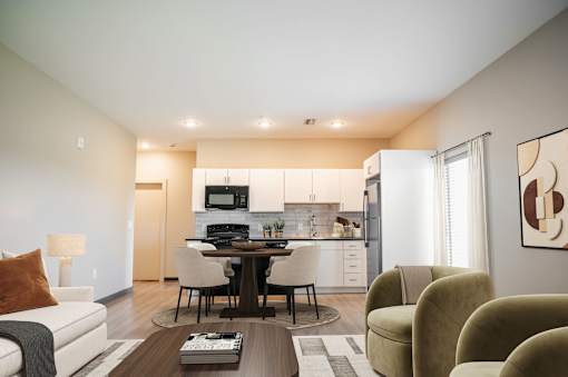 A modern living room with a dining area and kitchen in the background at Harbor Side at Conwood Flats Apartments in Uptown Memphis, TN
