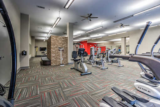 A gym with a variety of exercise equipment including treadmills, elliptical machines, and weights at Highland Row Apartments, TN, 38111
