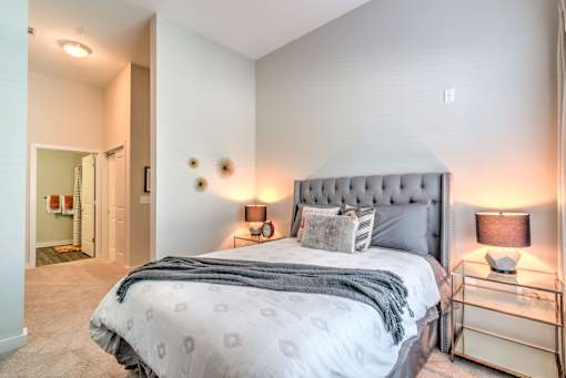A bedroom with a large bed and a nightstand with a lamp at Highland Row Apartments, Memphis, TN,  38111