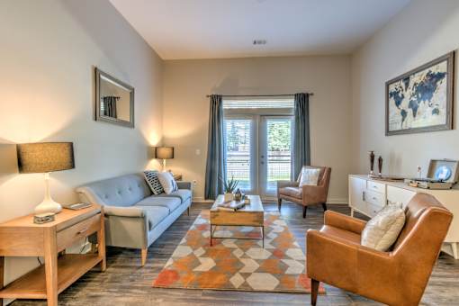 A living room with a grey couch, a brown chair, and a wooden coffee table at Highland Row Apartments, Memphis, 38111