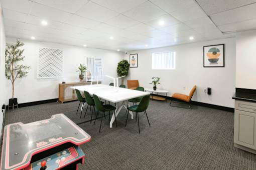 A conference room with a white table, chairs, and a foosball table.