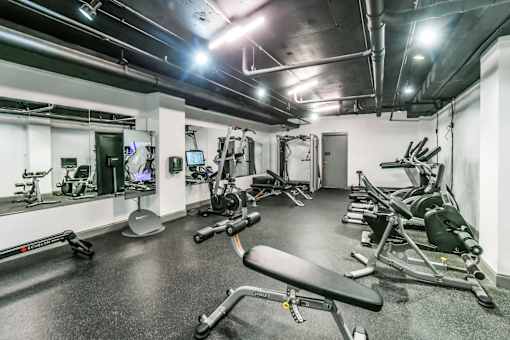 A gym with a variety of equipment including treadmills, weights, and exercise machines.