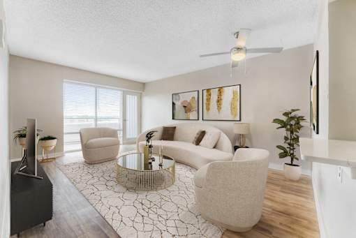 A living room with a white sofa, a glass coffee table, and a TV.at Iris Luxury Apartments, Memphis, TN  