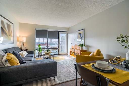 A living room with a grey couch, yellow chairs, and a dining table.at Iris Luxury Apartments, Tennessee, 38105