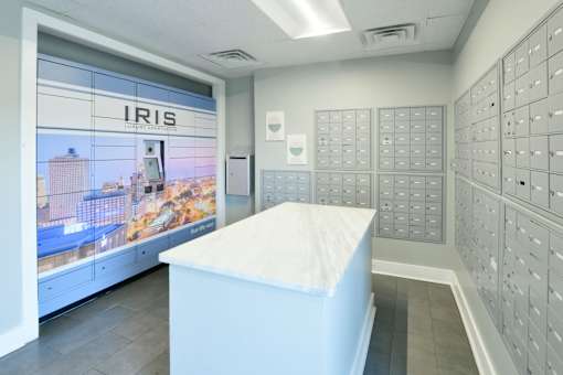 A white reception desk in front of a wall of mailboxes and a window showing a cityscape.