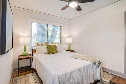 a bed with a white comforter and green accent pillow at Kiwi Goji Apartments, Memphis