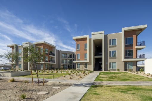 an exterior view of an apartment complex with grass and a sidewalk