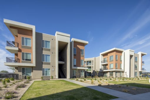 a row of apartment buildings with green grass and a blue sky