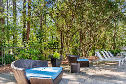 A patio with a blue cushioned chair and a white chair. at Manchester at Mansell, Georgia 