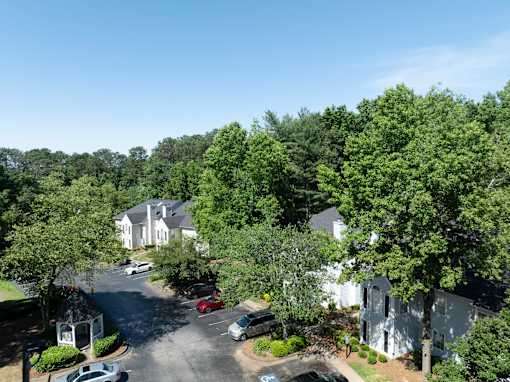 A tree-filled street with cars and houses. at Manchester at Mansell, Roswell, GA 30076 