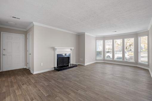 A living room with a fireplace and wood flooring. at Manchester at Mansell, Roswell, GA