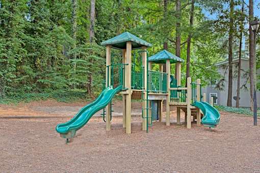 A playground with a green slide and a wooden structure. at Mill House at East Cobb, Marietta, 30067 