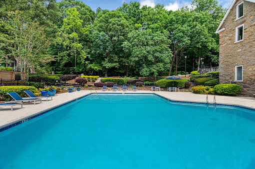 A large swimming pool surrounded by trees and a stone building. at Mill House at East Cobb, Marietta Georgia 