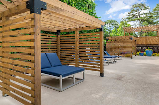 A wooden pergola with a blue cushioned bench underneath it. at Mill House at East Cobb, Marietta 