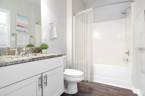 A white toilet sits in a bathroom next to a shower.