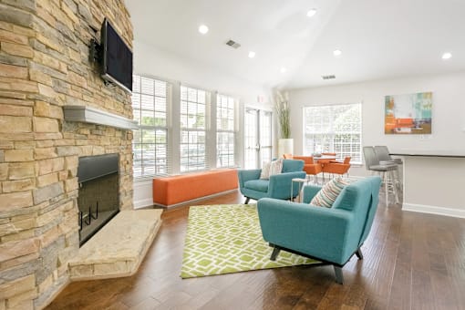 A living room with a stone fireplace and a flat screen TV mounted above it.