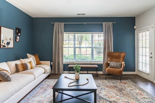 A living room with a white couch, a coffee table, and a chair.