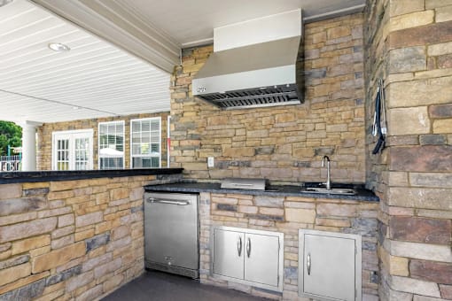 A kitchen with a stone wall and a stainless steel dishwasher.