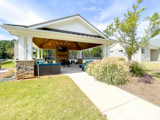 A white house with a covered patio and a stone pillar.
