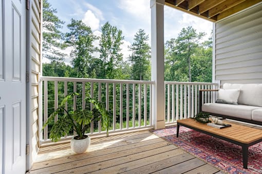 A wooden deck with a white sofa and a potted plant.