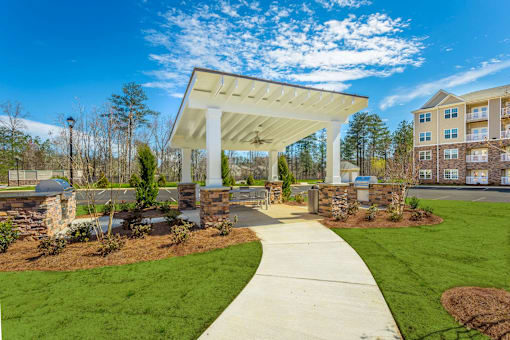 A white covered walkway leads to a building with a stone pillar on each side.