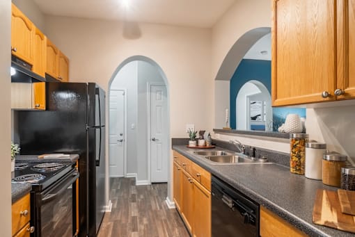 A kitchen with wooden cabinets and a black refrigerator.