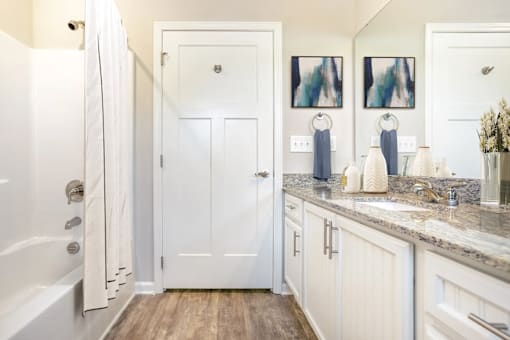 A white bathroom with a tub, sink, and mirror.