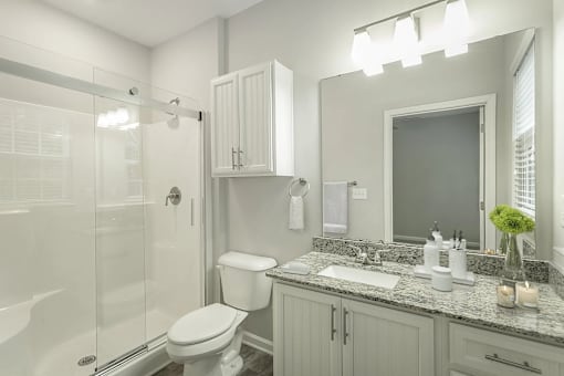 A white bathroom with a toilet, sink, and mirror.