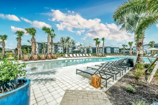 a swimming pool with lounge chairs and palm trees at Livano Nature Coast, Spring Hill, FL 34608