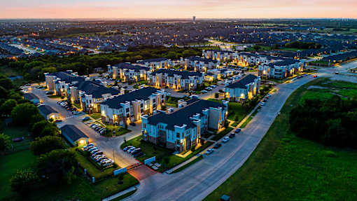 A residential area with houses and parked cars is shown at dusk.