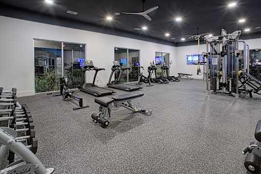 A spacious gym with a variety of equipment including treadmills, elliptical machines, and weight machines.