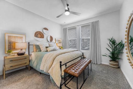 A bedroom with a bed, a bench, and a plant.