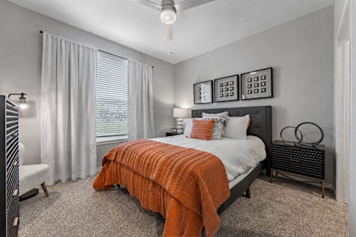 A bedroom with a bed covered in an orange blanket.