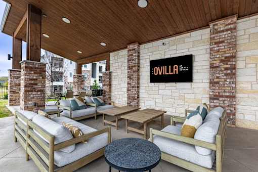 A patio with a couch, chairs, and a table with a sign that says "OVILLA".