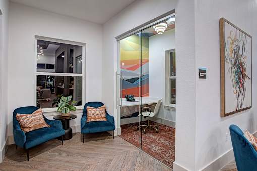 Two blue chairs with orange pillows in a room with a painting on the wall.