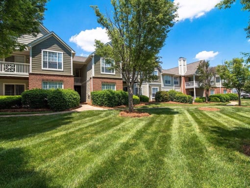 Meticulously maintained grounds with mature trees surround the soft green paint and brick exterior apartment homes at Autumn Park Apartments, Charlotte, NC 28262