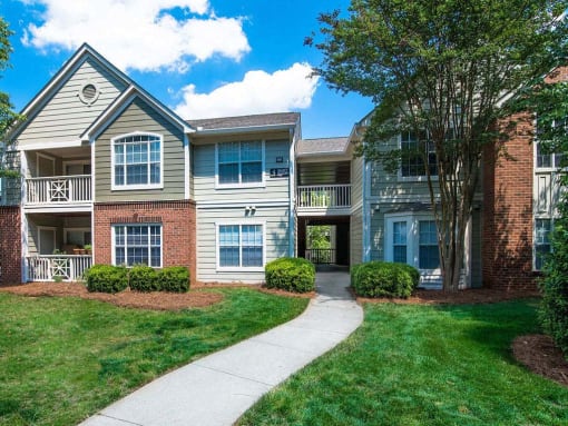 Meticulously maintained grounds with mature trees surround the soft green paint and brick exterior apartment homes at Autumn Park Apartments, Charlotte, NC 28262