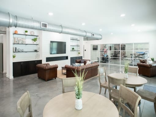 a living room with couches tables and chairs and a tv at Lakeland Town Square Apartments, Tennessee, 38002