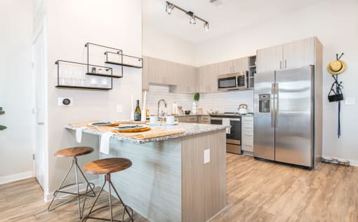a kitchen with stainless steel appliances and a bar with stools at The Baxly, Georgia , 31401