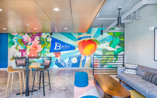 a lobby with a colorful mural on the wall and a couch and tables at The Baxly, Savannah, Georgia