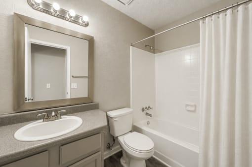 A bathroom with a toilet, sink, and shower.