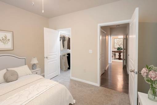 A bedroom with a large bed and a hallway leading to another room.