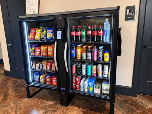 A black vending machine with a variety of snacks and drinks inside.