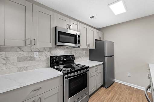 A kitchen with a stove, oven, refrigerator, and microwave. at Station Heights, Alpharetta Georgia 