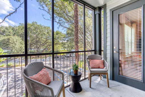 a porch with two chairs and a table and a window at The Beck at Hidden River, Florida
